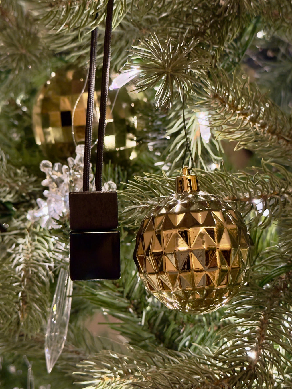 Gold geometric ornament hanging on a Christmas tree